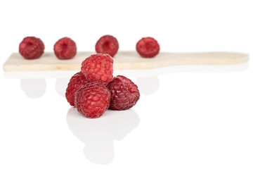 Group of seven whole fresh red raspberry on wooden cutting board isolated on white background