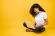 pretty young black african woman sitting with laptop and earpods isolated over yellow