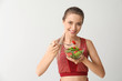 © Pixel-Shot - Sporty woman eating healthy vegetable salad on light background. Diet concept
