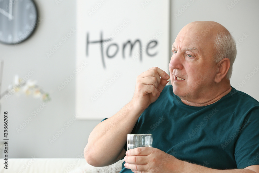 Elderly man taking medicine at home
