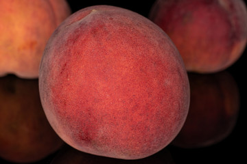 Group of three whole sweet red peach front focus isolated on black glass