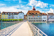 View on the beautiful picturesque historic buildings with cafe and restaurants from Rathaussteg Bridge over Reuss River in Old Town Lucerne.
