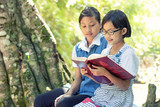 Fototapeta Niebo - Cute little girl reading a book outdoors