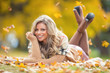 © weyo - Attractive young woman with sensual smile lies in autumn park