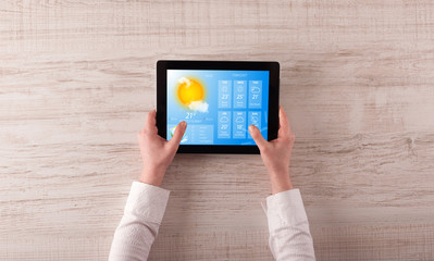 man hand checking weekly weather forecast on tablet