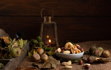 Variation of dried nuts on a autumn theme background with leafs and candle light.