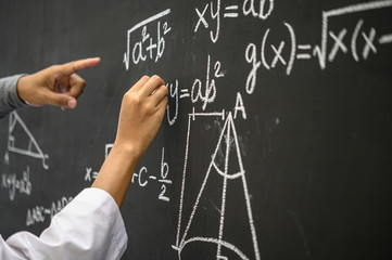 The hand that is written with the white chalk and the hand that shows the formula on the blackboard.