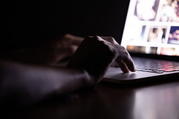 Hand of a man using laptop computer working at night