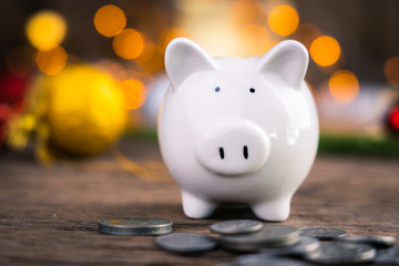 Piggy bank with coins on wooden table with yellow bokeh background. Gift for party festival concept.