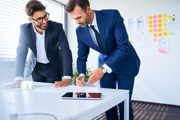 Wall Mural - Two businessmen reviewing business documents in office