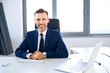 © baranq - Portrait of smiling businessman sitting in office and looking at camera