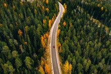 Aerial View Of Autumn Color Forest In The Mountains And A Road With Car In Finland Lapland.