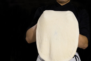 Wall Mural - Chef preparing dough for pizza rolling with hands isolated in black background.