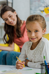 Wall Mural - selective focus of happy kid studying near babysitter at home