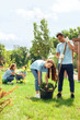 © Viktoriia - Volunteering. Young people volunteers outdoors planting trees boy helping girl digging plant from pot cheerful