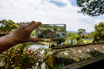 Wall Mural - Photographing with smartphone in hand. Travel concept. Water Palace of Tirta Gangga in Bali.