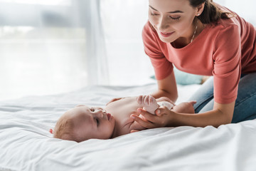 Wall Mural - beautiful mother touching cute infant baby while doing massage at home