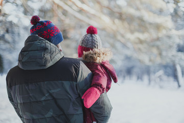 father holds his daughter in his arms in the winter forest with his back, his face is not visible 1