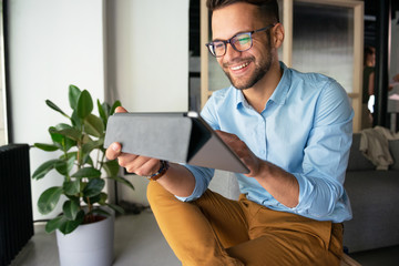 Wall Mural - Young smiling Man typing on digital tablet	