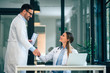© bnenin - Two confident doctors standing shake their hands in medical office.