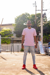 Wall Mural - Full body shot of happy young African man with sunglasses smiling outdoors