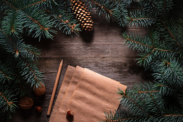 Wall Mural - Christmas frame from fir branches on a background of an old gray board around an open notebook with blank sheets. Frame of fir branches. Christmas card blank concept.