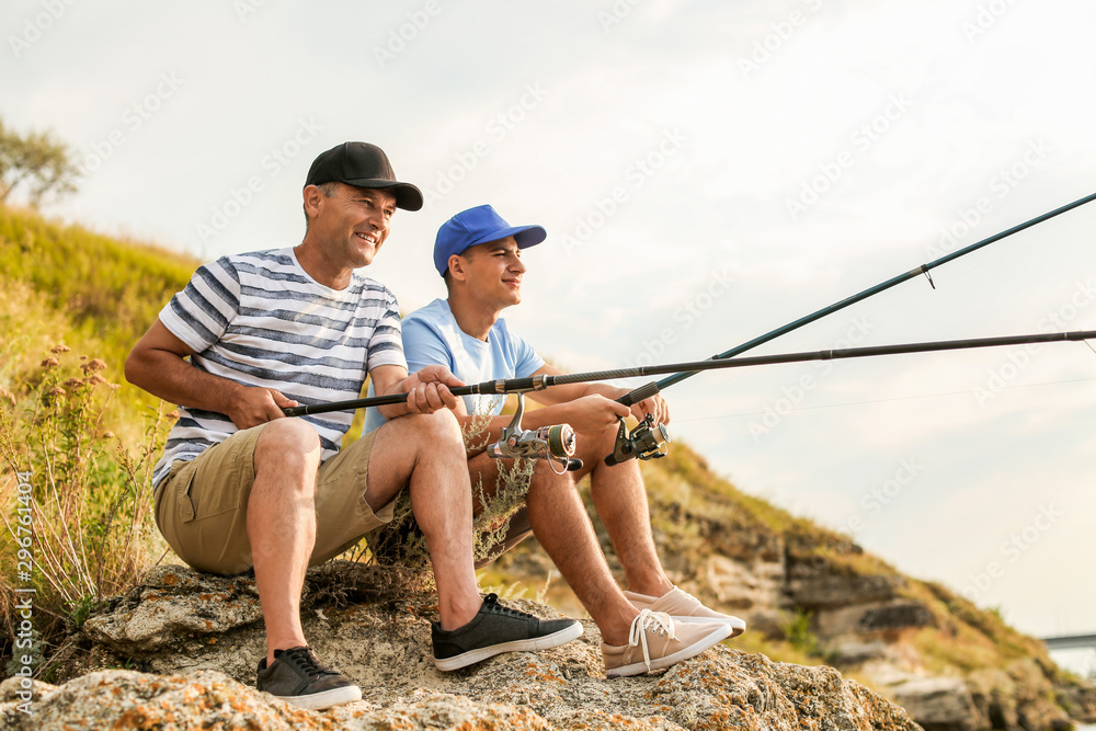 Young man and his father fishing on river