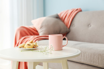 Cup of coffee and cookies on table in room