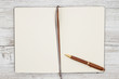 Blank brown journal with pen on a weathered whitewash wood background