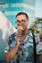 Young Fashionable Man Eating Ice Cream In A Cone In The City At Sunset