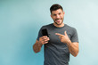 © AntonioDiaz - Handsome Man Holding Smartphone Against Plain Background