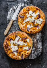 Wall Mural - Cheesy autumn veggie flatbread. Pumpkin, sweet potato, red onion, mozzarella pizza on dark background, top view