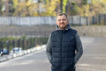 Portrait of a middle aged man with a beard against the backdrop of an city street.