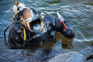 industrial diver with scuba gear and hammer working in the water at the shore reinforcement, copy space