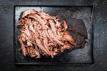 Wall Mural - Traditional barbecue wagyu pulled beef offered as top view on a rustic board in a metal tray