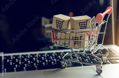 Cuadros en Lienzo Shopping online concept - Parcel or Paper cartons with a shopping cart logo in a trolley on a laptop keyboard