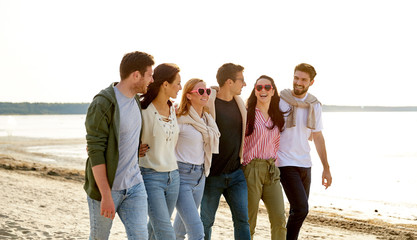 Wall Mural - friendship, leisure and people concept - group of happy friends walking along beach in summer