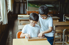 Two Students Using An Abacus In Empty Classroom