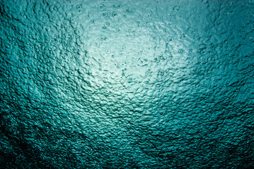 a shot taken from beneath the surface of the sea looking up at the sky. the light patch is the sun o