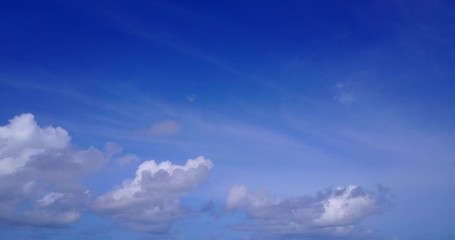 big white clouds on a violet blue sky hover over the ocean, wide pan view moving slowly