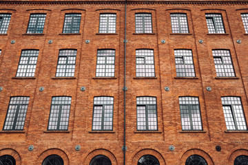 Red brick classic industrial building facade with multiple windows background. 