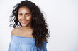 Beauty, wellbeing and women concept. Charming curly-haired african american girl in blue blouse smiling joyfully, gaze with happy tender expression camera, standing white background