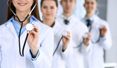 Wall Mural - Group of doctors holding stethoscope head close-up. Physicians ready to examine and help patient. Medical help, insurance in health care, best treatment and medicine concept