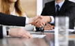 © Iryna - Businessman shaking hands with his colleague or partner above the glass desk in modern office, close-up. Unknown business people at meeting. Teamwork, partnership and handshake concept