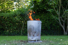 Close-up View Of A Home Made Metal Garden Incinerator Seen Burning General Household, Non Toxic Water In A Garden Setting.
