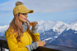 © ZoomTeam - Woman drinking warm tea in the rustic wooden terrace on mountain, winter alpine view, snow on peak