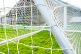Fototapeta Sport - Shallow focus of a newly delivered football goal located in a village park. Detail of the white netting and knots are visible.