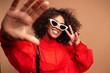 Portrait of beautiful young black woman taking selfie.Portrait of a pretty young afro american woman in retro style clothes smiling while standing and taking a selfie isolated over beige.