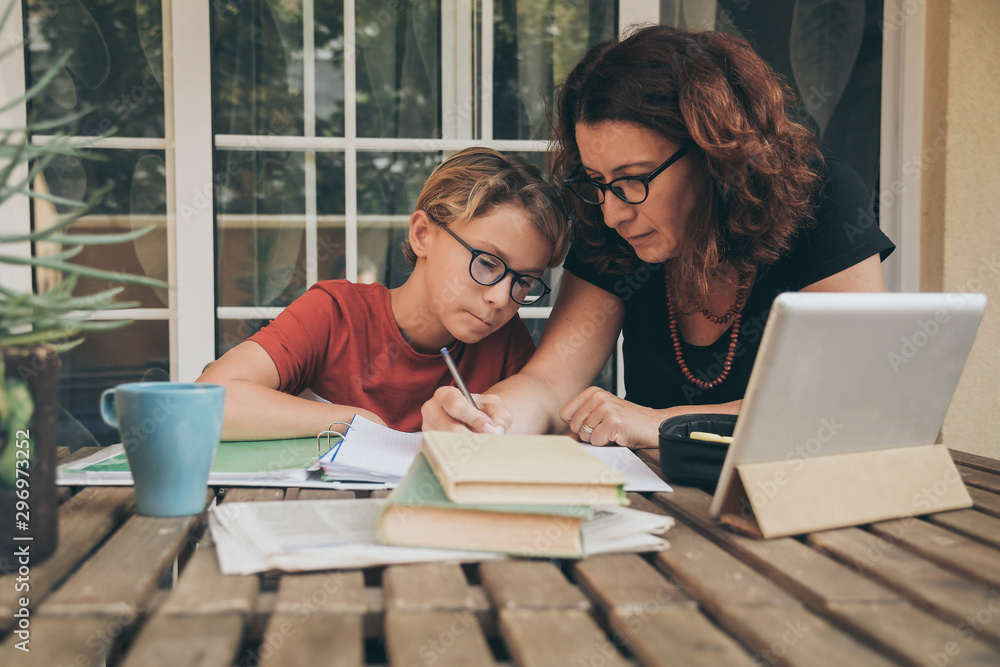 Home Homework Young student doing homework at home with school books, newspaper and ...