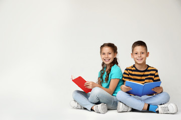 Wall Mural - Little children reading books on grey background. Space for text